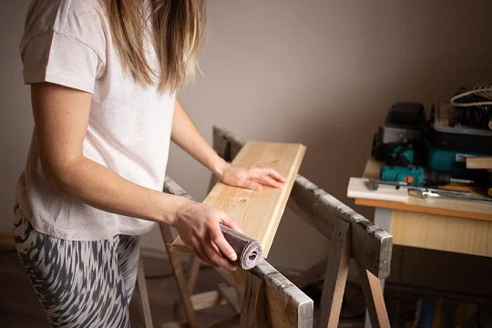 young woman sanding a wooden board with sandpaper