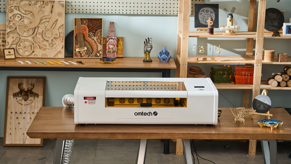 white laser machine with omtech on it in a woodshop