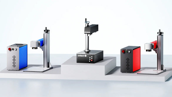 Three OMTech fibre laser marking machines (blue, black and red) on display for Q-switched and MOPA engraving and marking.
