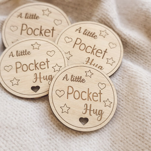 Wooden tokens with 'A little Pocket Hug' text on a textured fabric background