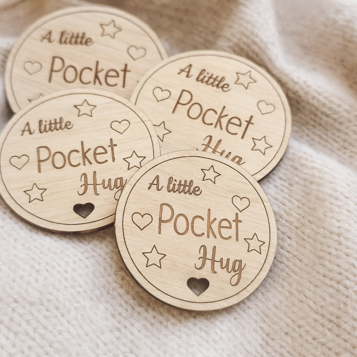 Wooden tokens with 'A little Pocket Hug' text on a textured fabric background