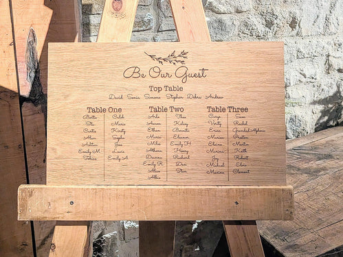 Wooden seating chart for a wedding with engraved names on a rustic background