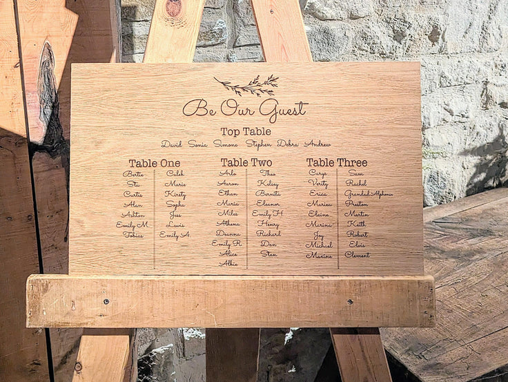 Wooden seating chart for a wedding with engraved names on a rustic background